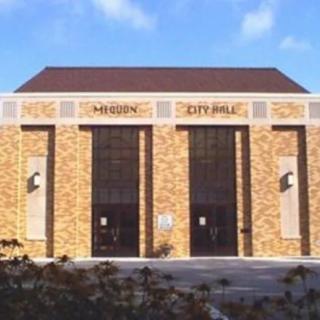 A brick city hall building under a clear blue sky.