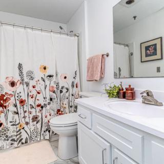 A clean and bright bathroom with a floral shower curtain and white cabinetry.