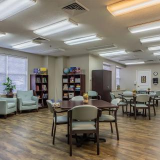 A well-lit room with tables, chairs, and bookshelves.