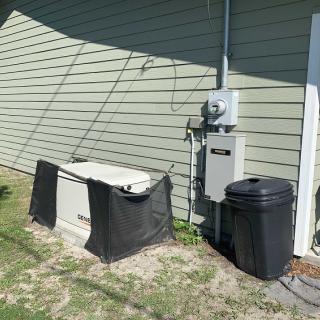 A home backup generator setup alongside utility equipment on the exterior of a house.