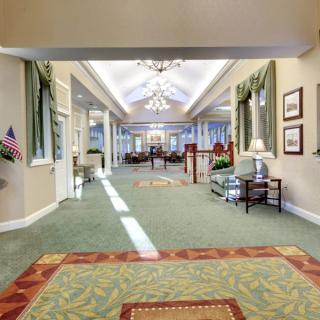 A well-lit lobby area with elegant chandeliers, carpeted flooring, and comfortable seating.