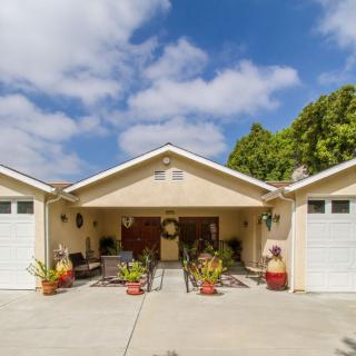 A suburban house with a driveway and two garages, surrounded by greenery.
