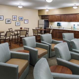 An inviting waiting room with comfortable seating and tables, featuring warm lighting and decorative elements.