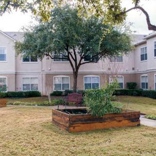 A serene courtyard featuring a garden with raised beds, surrounded by a residential building.