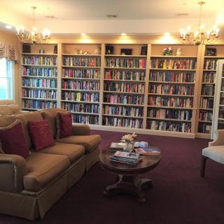 A cozy library room with shelves full of books, a comfortable sofa, and a coffee table.