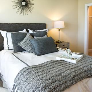 A cozy and modern bedroom with stylish gray bedding and decorative pillows.