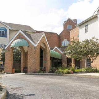 A welcoming entrance to a residential building, featuring distinct architectural elements and lush greenery.