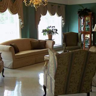 A classic living room with elegant furniture and decor, featuring a chandelier and large windows.