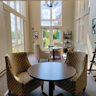 A cozy seating area filled with natural light, featuring stylish chairs and a round table.
