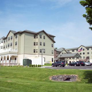 A hotel building with a well-maintained lawn and a parking lot in the foreground.