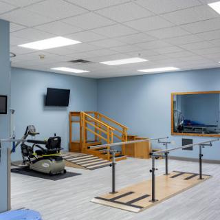 A well-equipped physical therapy room featuring exercise bars, a staircase for rehabilitation exercises, and various therapeutic equipment.