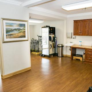 A spacious interior view of a kitchen area featuring wooden flooring and artwork on the wall.