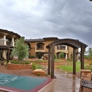 A scenic courtyard with a pathway and garden set against a building under a stormy sky.