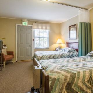 A cozy bedroom with two beds, a window, and warm lighting.