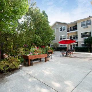 A view of an apartment complex patio area with garden planters and outdoor seating.
