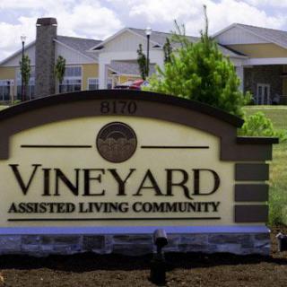 Entrance sign for Vineyard Assisted Living Community with buildings in the background.