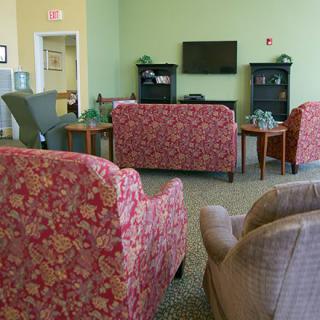 A cozy living room with floral-patterned sofas and an armchair, centered around a television.