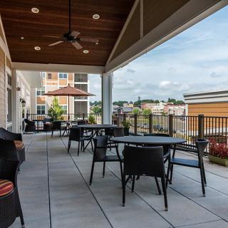A modern outdoor patio with tables and chairs overlooking a cityscape.