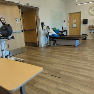 A therapy room equipped with exercise machines and a treatment table.