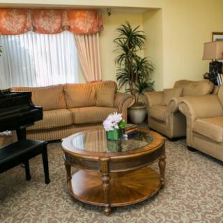 A cozy living room featuring a grand piano, comfortable sofas, and a decorative coffee table.