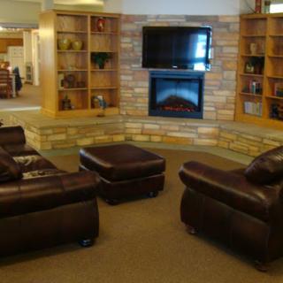 A cozy living room setup featuring leather sofas, a fireplace, and a wall-mounted television.