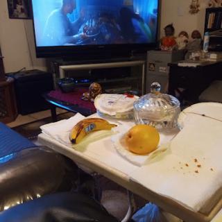 A cozy living room setup with fruit snacks and a movie playing on the TV.