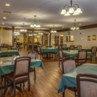 A cozy restaurant dining room with elegantly set tables and warm lighting.