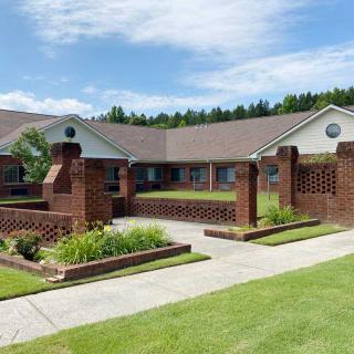 A well-maintained brick residential building with landscaped gardens under a clear blue sky.