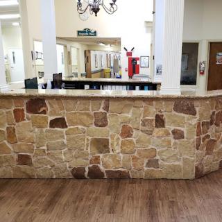 A reception area featuring a stone counter and wooden flooring.