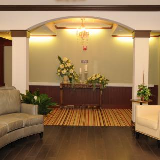 A cozy lobby area with elegant sofas, decorative plants, and a chandelier.