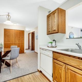 A modern kitchen with wooden cabinets and an open dining area, featuring contemporary design elements.