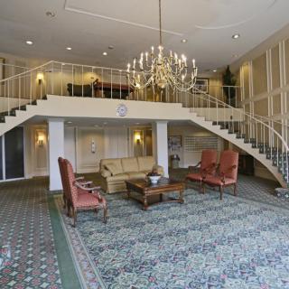Spacious hotel lobby featuring a grand chandelier, elegant staircase, and comfortable seating areas.