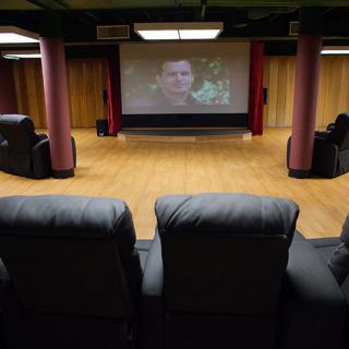 A cozy home theater setup with leather chairs facing a large projector screen.