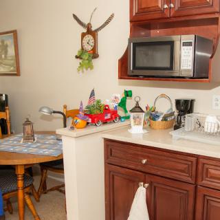 A cozy kitchen and dining area with a microwave, wooden cabinets, and various kitchen utensils.