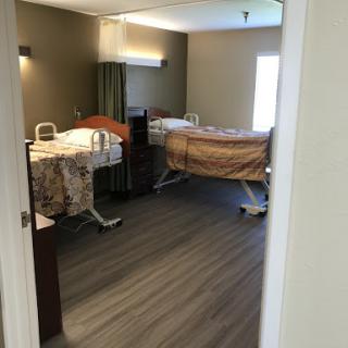 A view of a patient room in a healthcare facility with two beds and modern furnishings.