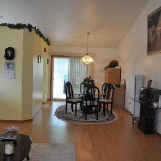 A cozy dining room with a wooden table and chairs, featuring a decorative light fixture and a rug on the wooden floor.