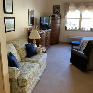 A cozy living room with a sofa, armchair, and television near a window.