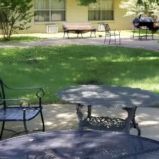 A peaceful garden setting with patio furniture and lush greenery.