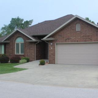 A suburban brick house with a two-car garage and a neatly maintained front yard.