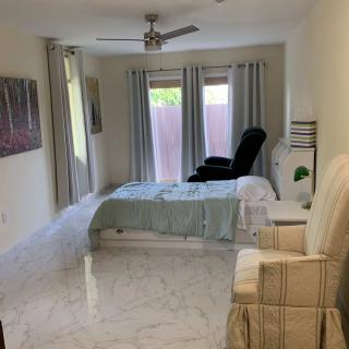 A bright and cozy bedroom with a bed, armchair, and large windows with curtains.