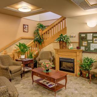 A cozy lobby area featuring comfortable seating, a fireplace, and decorative plants.