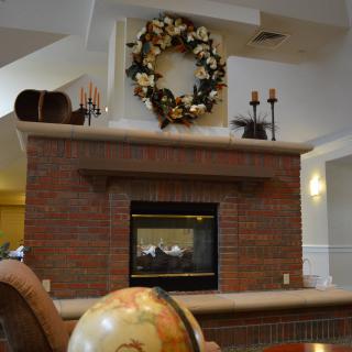 A cozy brick fireplace decorated with a wreath and candles, creating a warm and inviting atmosphere.
