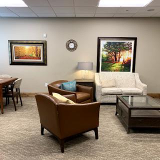 A cozy living room setup with a white sofa, brown armchairs, and decorative artwork on the walls.
