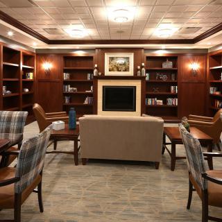 A cozy library reading room featuring comfortable seating, wooden bookshelves, and a warm ambiance.
