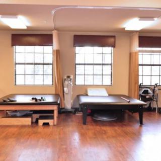 A spacious physical therapy room with treatment tables and exercise equipment.