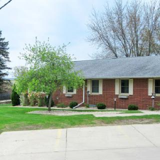 A charming brick residence surrounded by greenery, featuring a well-maintained driveway.