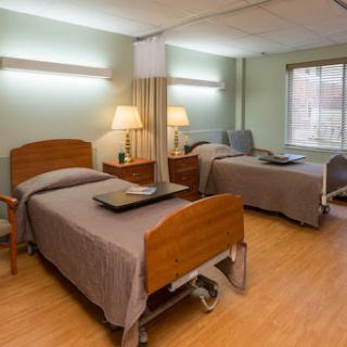A well-lit patient room in a hospital featuring two adjustable beds and warm, inviting decor.