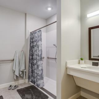 A modern bathroom with a shower area, towels, and a sink with a mirror.