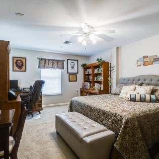 A cozy bedroom with a bed, desk, and bookshelf.