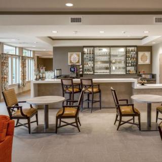 A modern lounge with bar seating and tables, featuring comfortable chairs and inviting decor.